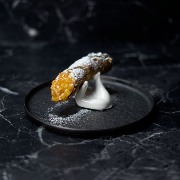 "Cannolo Siciliano - Dessert typique de la Sicile, biscuit farci à la ricotta de brebis, julienne d’agrumes confits et pistache"